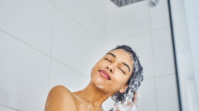 woman washing her hair in shower with shampoo