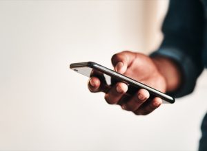 Cropped shot of an unrecognizable businessman standing alone in his home office and texting on his cellphone