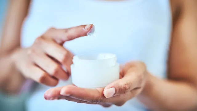 close up of woman putting her finger in moisturizer
