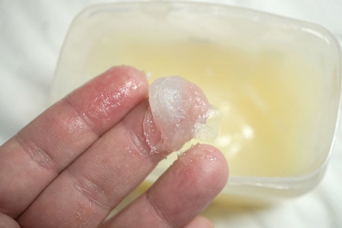 close up of fingers with petroleum jelly on them and tub below