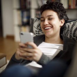 Young woman enjoying a relaxing weekend at home laughing while on phone