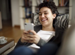 Young woman enjoying a relaxing weekend at home laughing while on phone