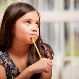 little girl holding pencil and thinking