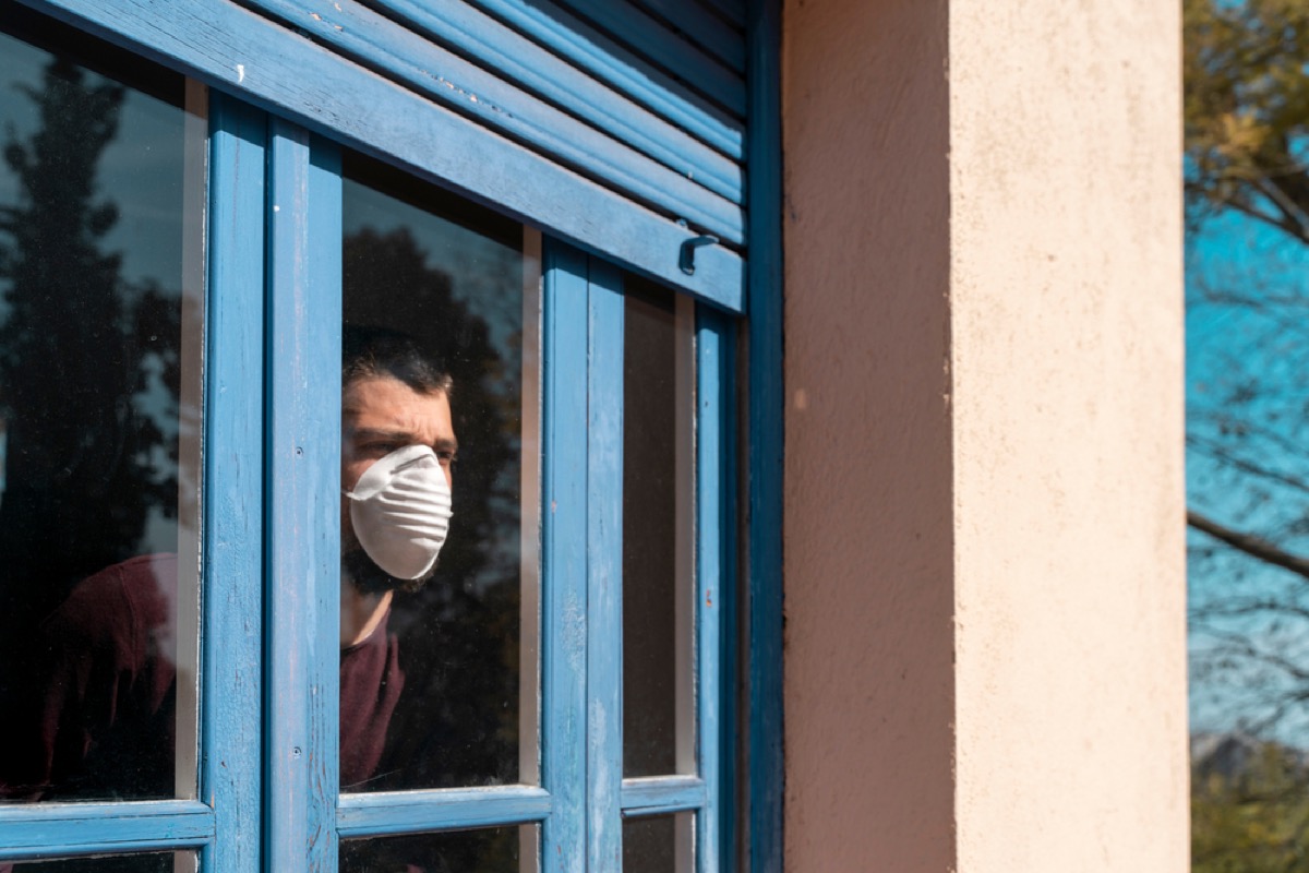 man in mask staring out window
