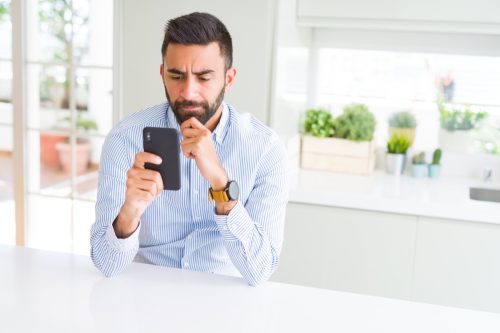 business man using smartphone serious face thinking about question, very confused idea