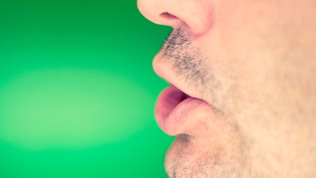 Man's lower part of face mid-word on green background