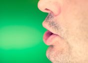 Man's lower part of face mid-word on green background