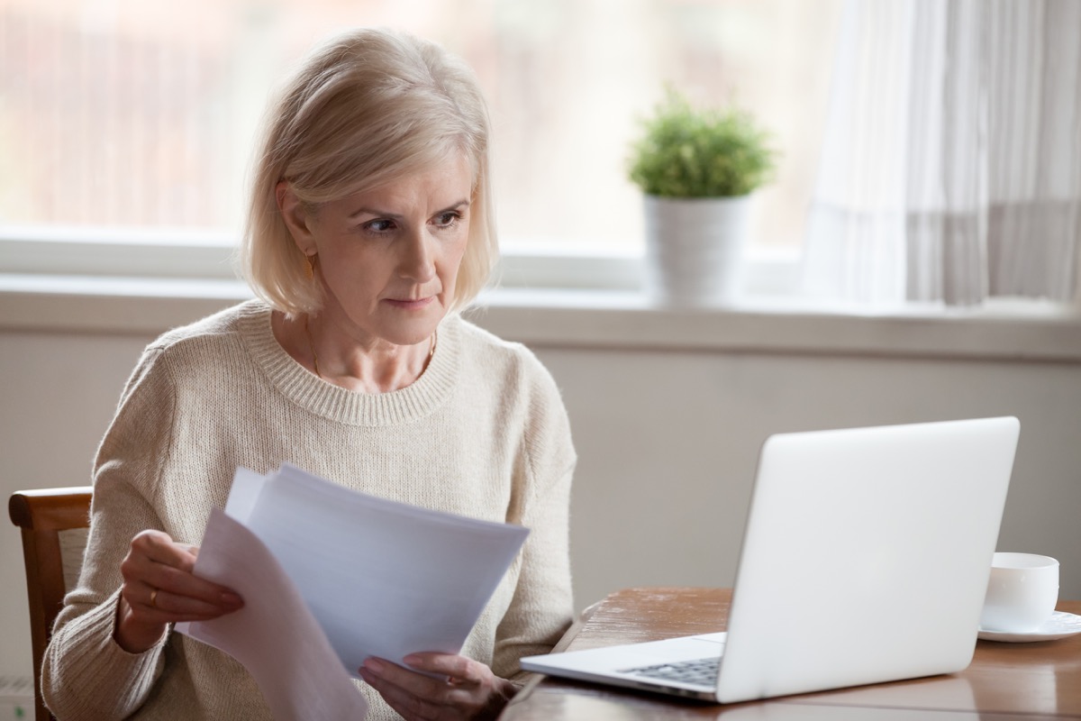 older white woman on video call holding papers while wfh
