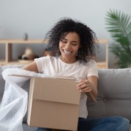 Woman opening box with a lot of bubble wrap on couch