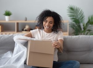Woman opening box with a lot of bubble wrap on couch
