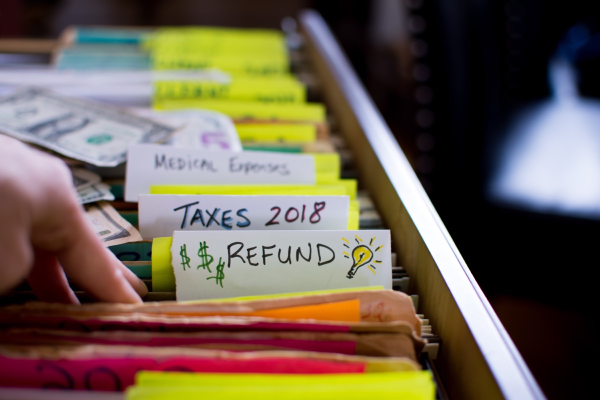 Tax refund conceptual tax season tax preparation photography with files and tax forms in filing cabinet and words refund and taxes 2018 written on file folders with light bulb for ideas and US dollar cash in background