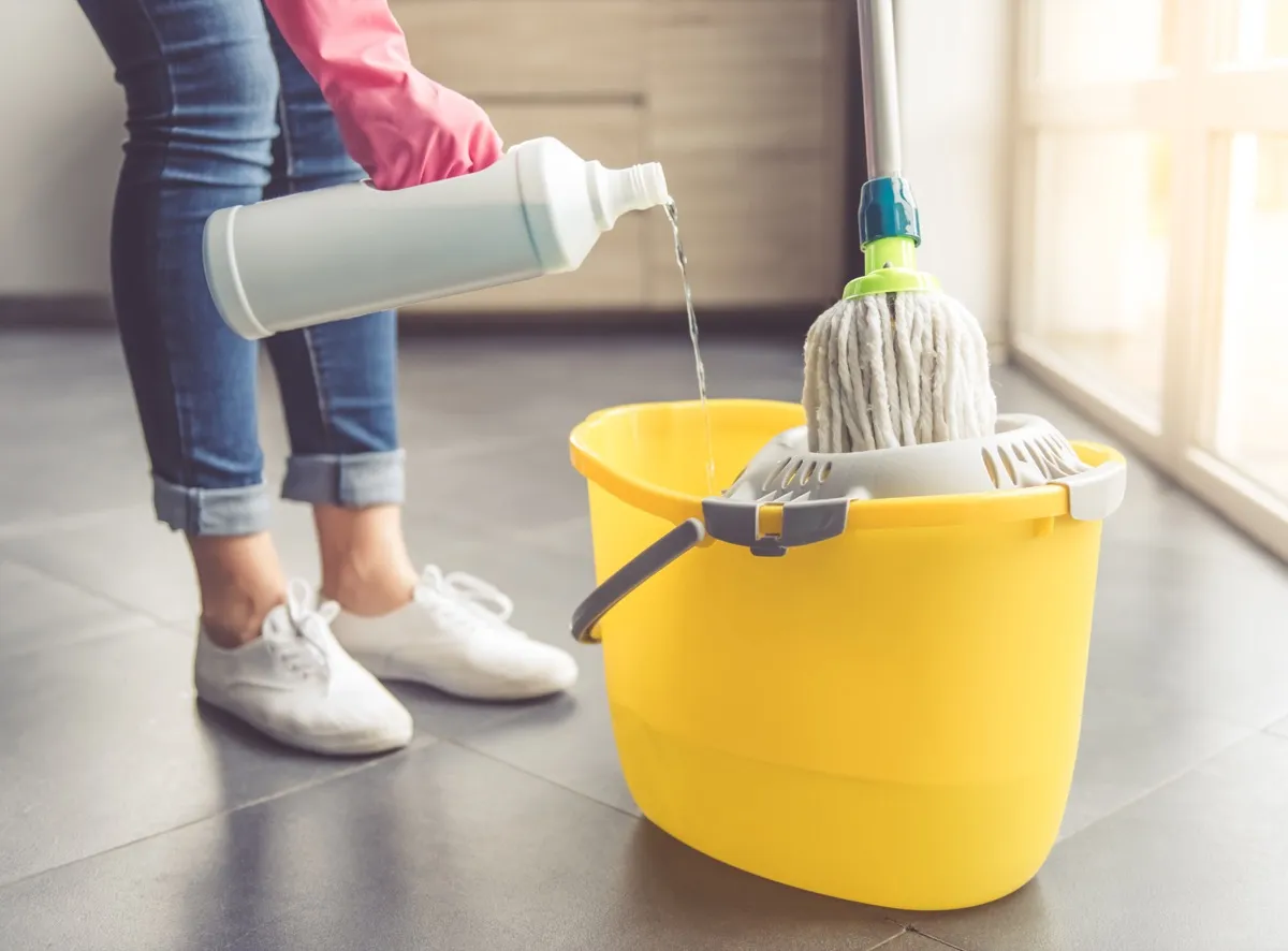 woman pouring cleaning chemicals in mop bucket