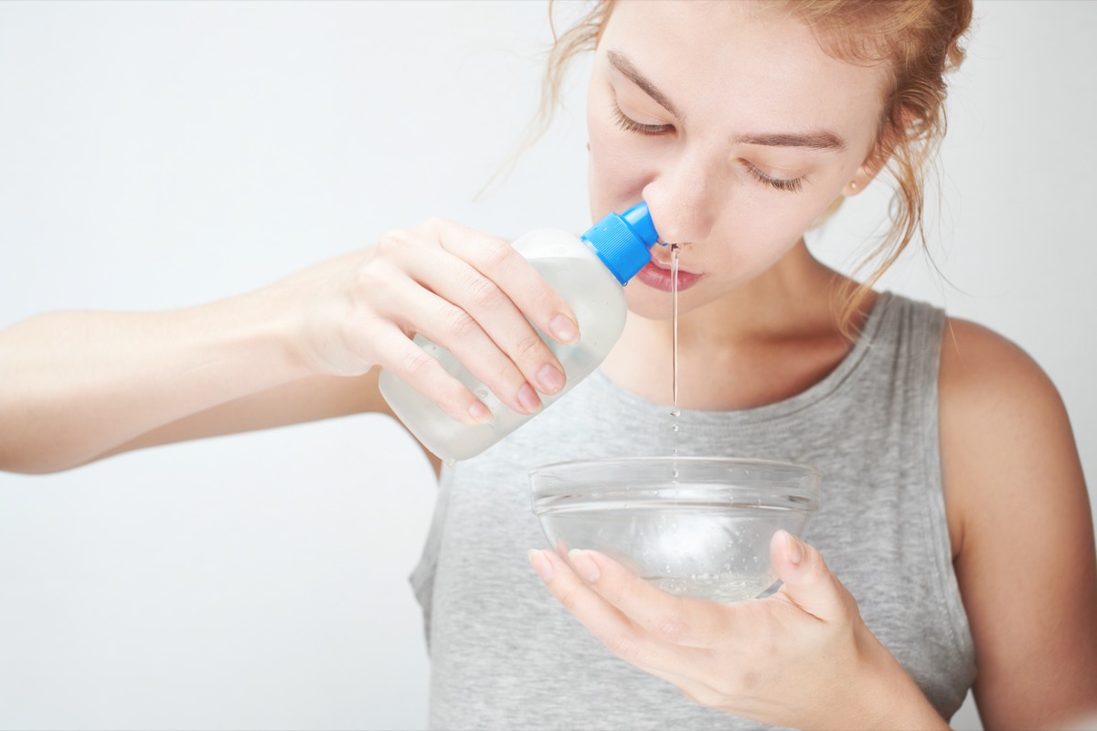 woman squirts saline in her nose
