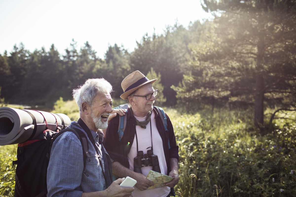 Close up of two senior male friends having a hike through the forest