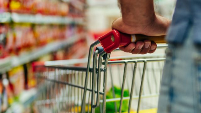 closeup of white man's arm holding on to cart in grocery store