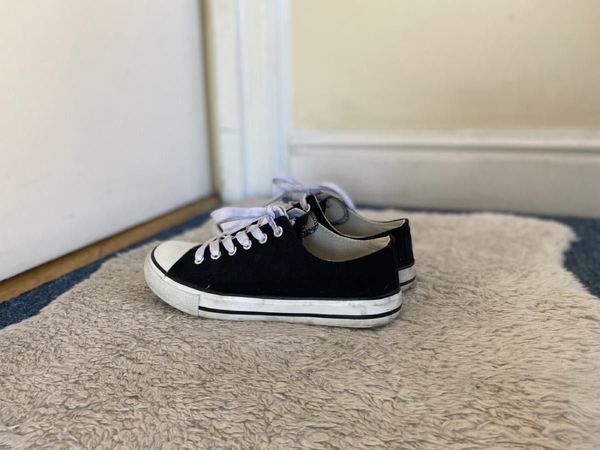 black tennis shoes on a carpet by a door