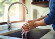 Shot of an unrecognizable woman washing her hands in the kitchen sink