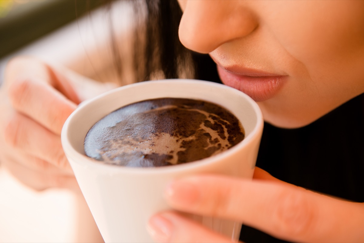 Woman trying to smell a cup of coffee
