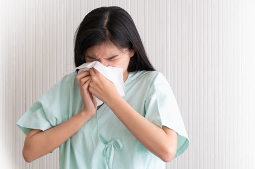 Nurse sneezing or blowing nose into tissue