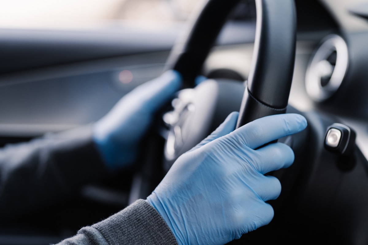 hands in blue gloves holding steering wheel