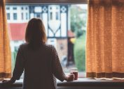 Rear view of woman at home staring through the window