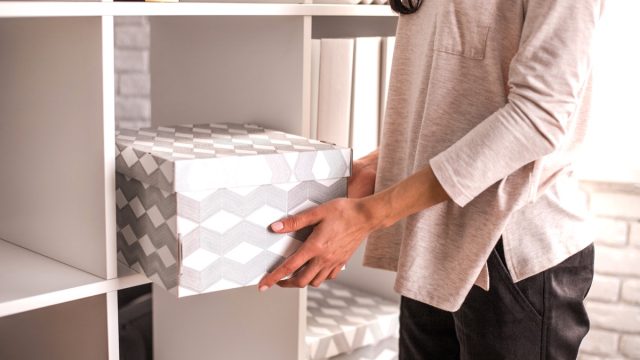 woman putting box into cube organizer shelving