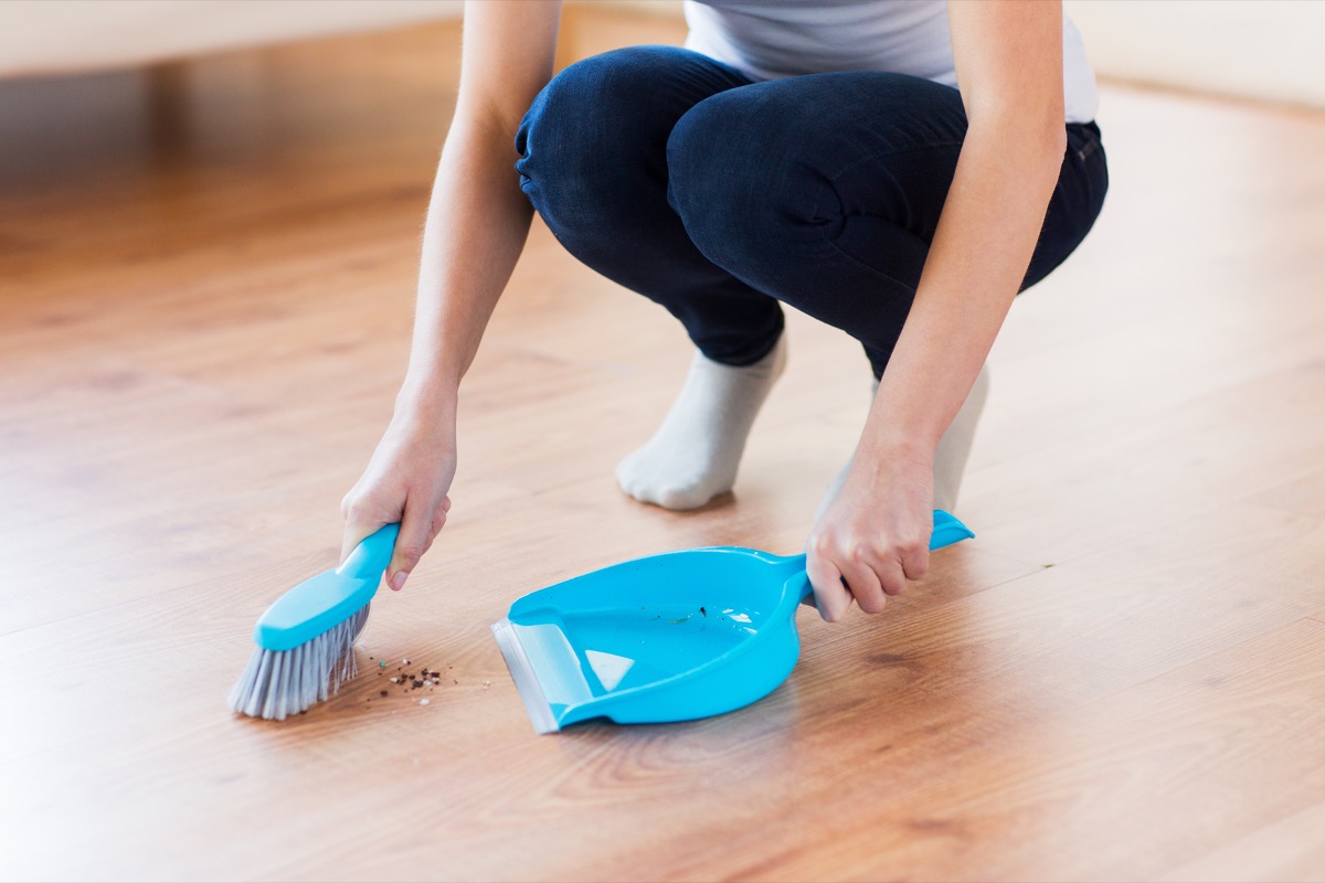 white woman sweeping floor 