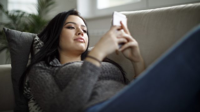 young asian woman texting on couch