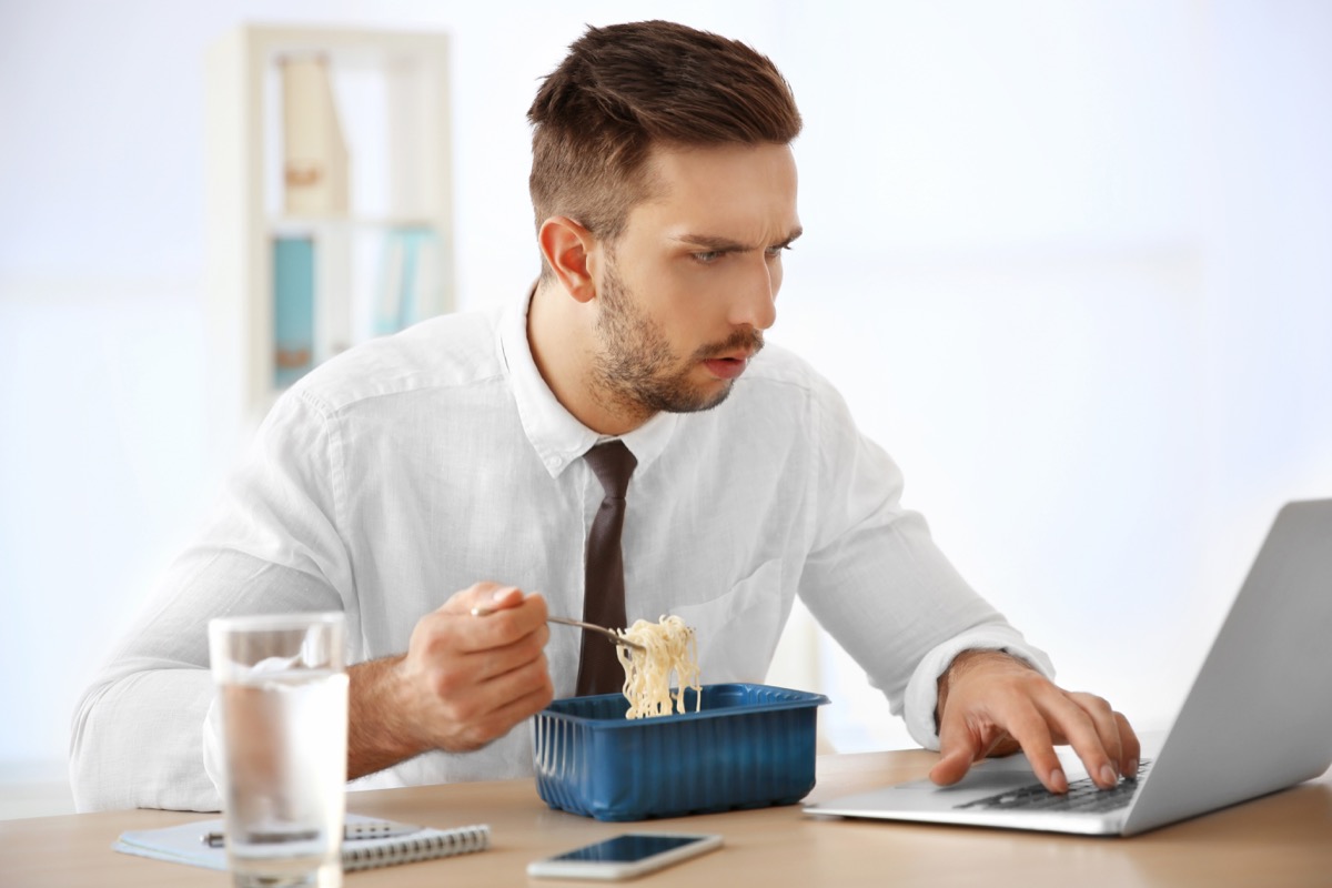 Man eating noodles while working from home