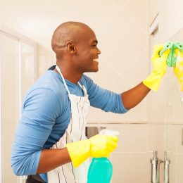 young happy black man cleaning bathroom mirror