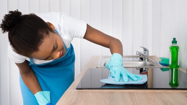 Young black woman cleaning cooktop