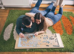 young white couple doing jigsaw puzzle on floor