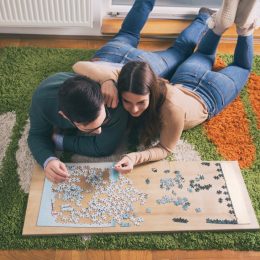 young white couple doing jigsaw puzzle on floor