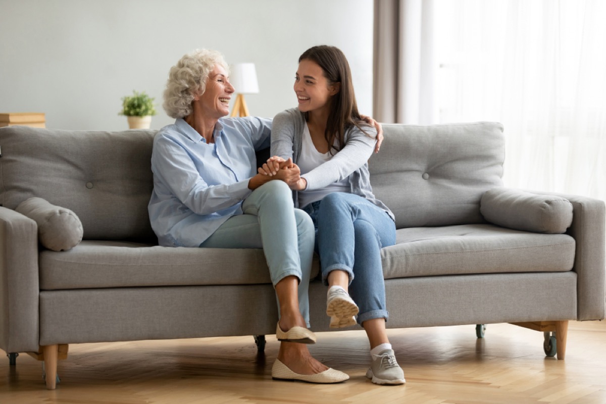 young woman and grandmother sit on couch