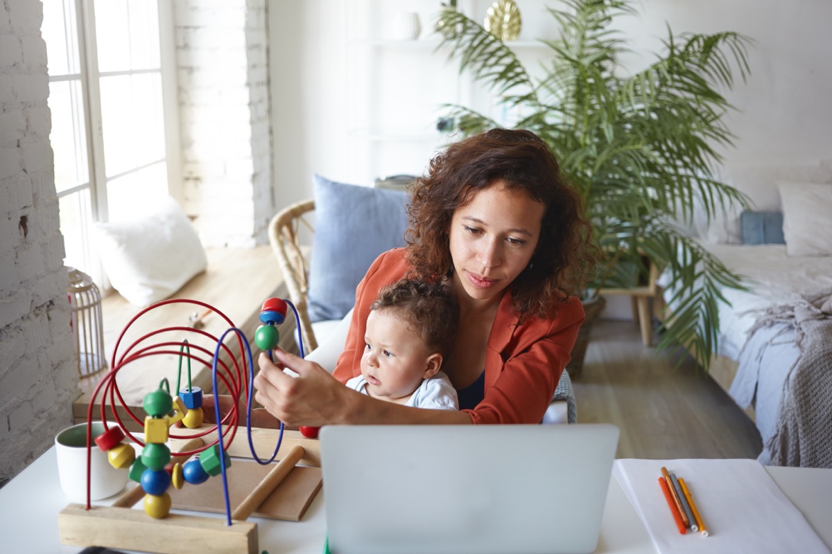 young black woman working from home with toddler son in lap