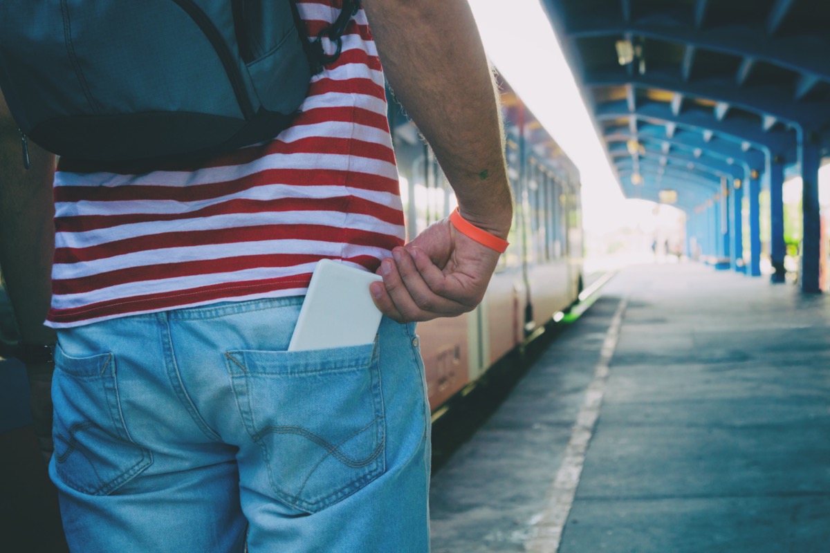 Man in train station with phone in back pocket