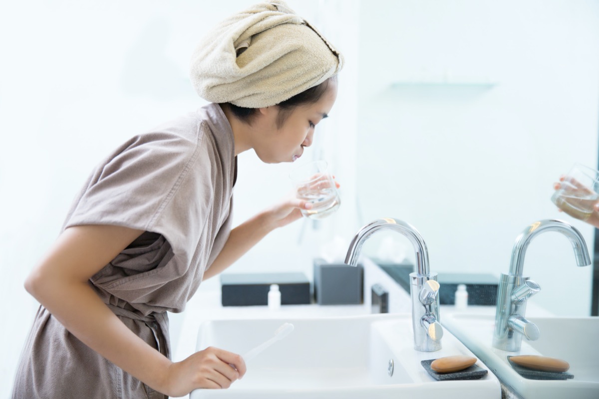 Asian woman using mouthwash in bathroom