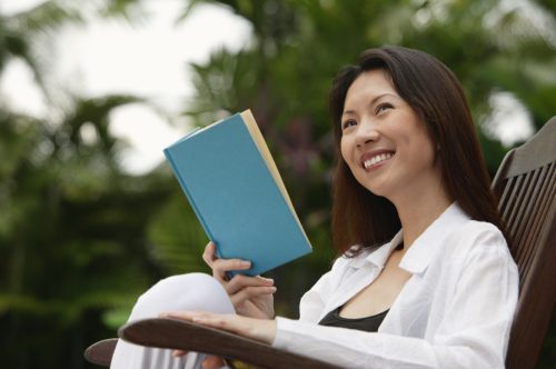 30-something woman reading a book outdoors