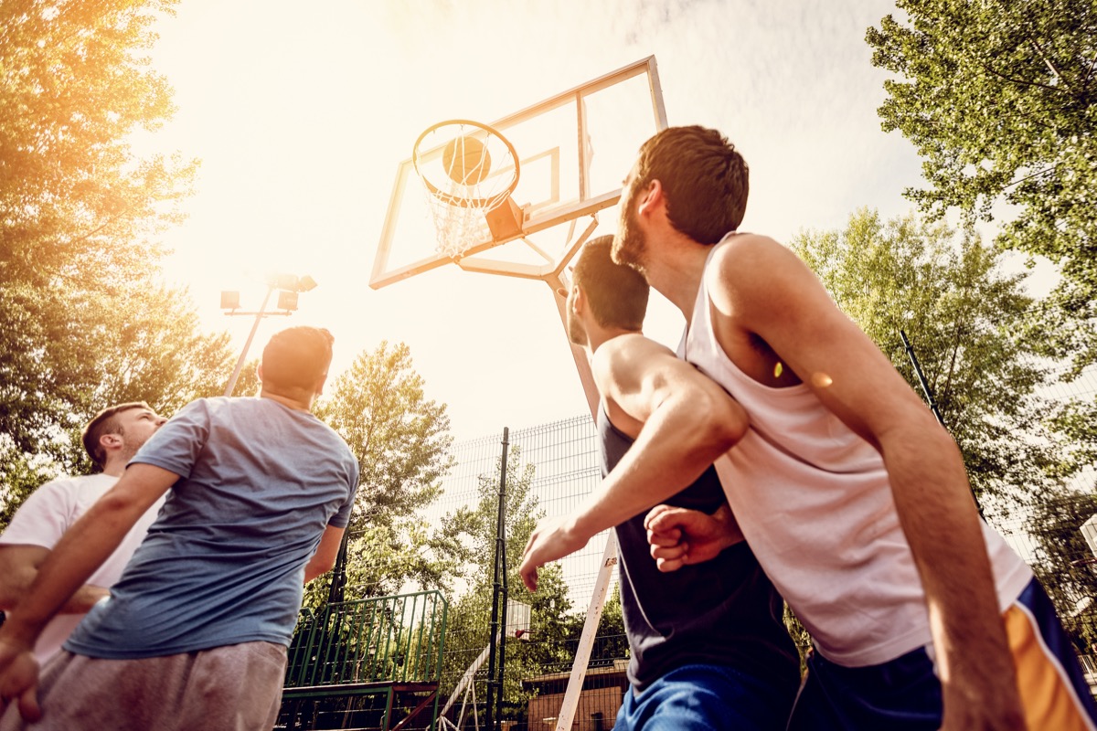 four men play basketball outdoors