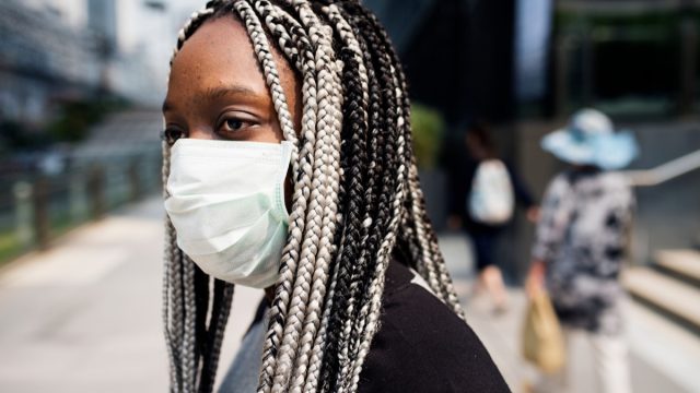 black woman with braids standing outside wearing face mask