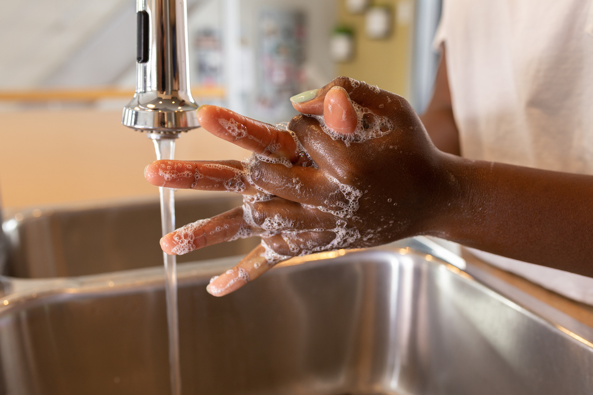 black woman washing hands at sink