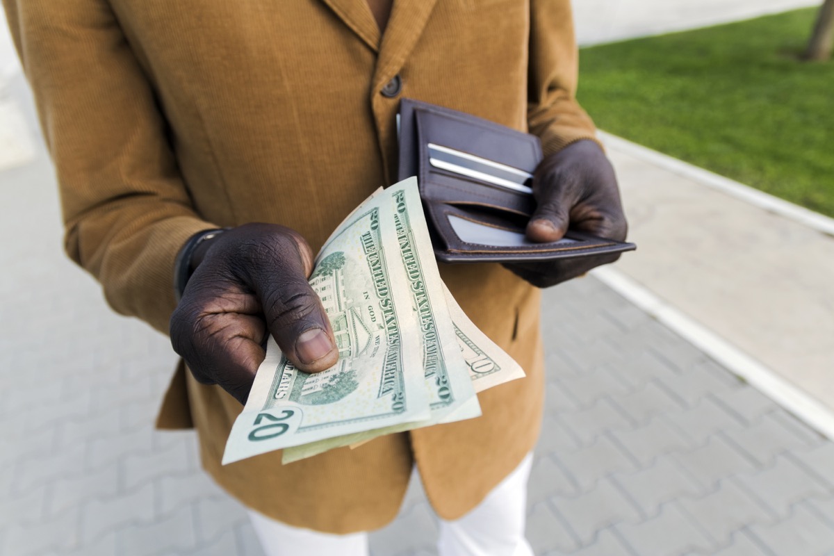 Cropped shot of businessman gets money from the wallet. Purse with dollars in their hands. Businessman's hand in suit takes out dollar money from a wallet