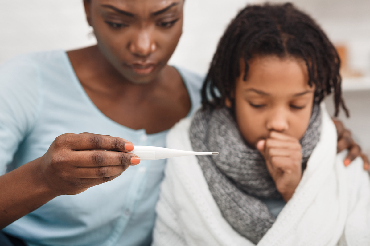 Worried black mother looking at thermometer, ill daughter coughing