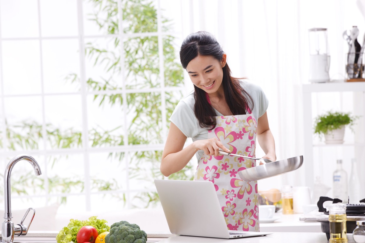 Woman cooking using laptop for recipe directions
