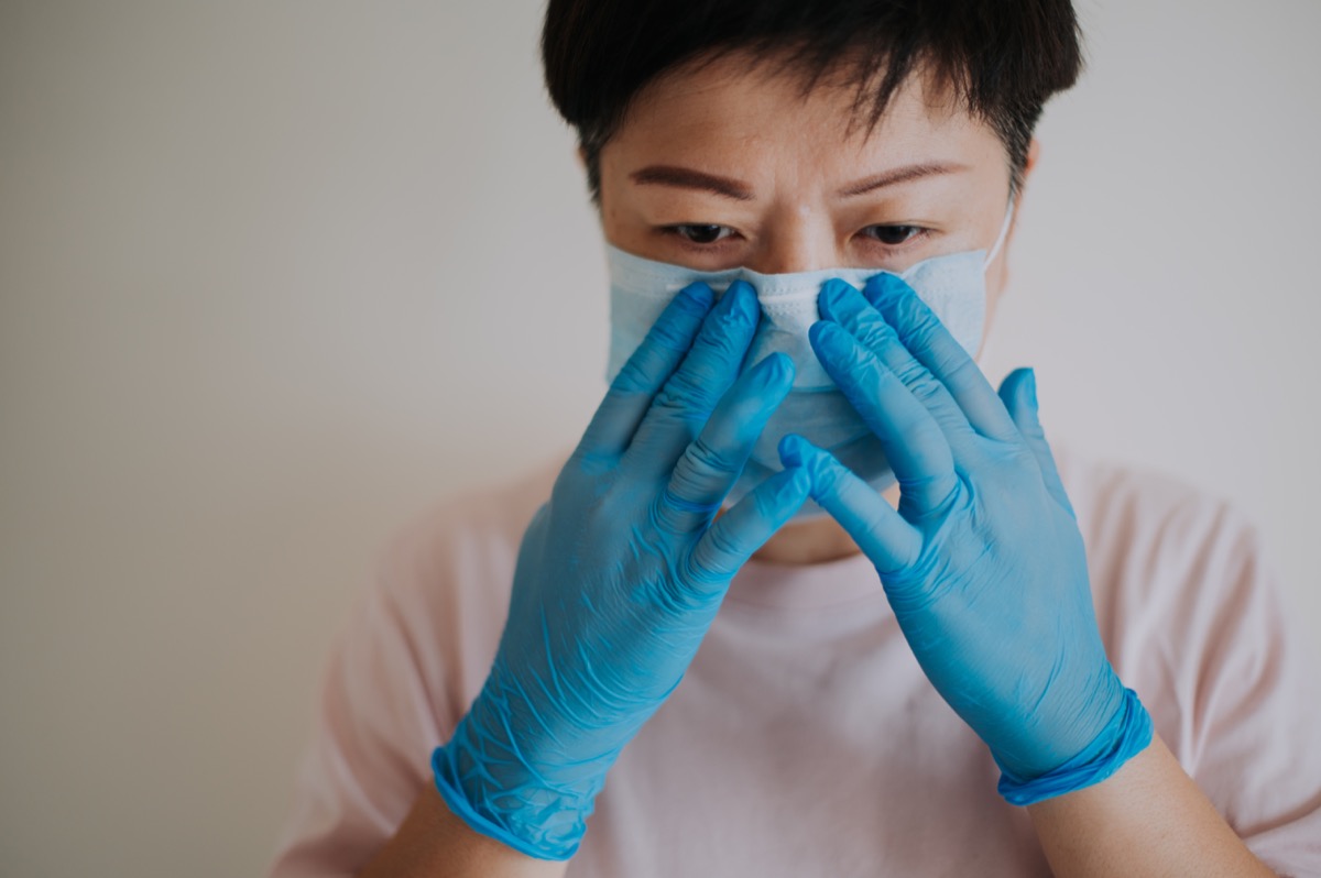 a female with her latex surgical glove wearing her face mask before going out