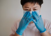a female with her latex surgical glove wearing her face mask before going out