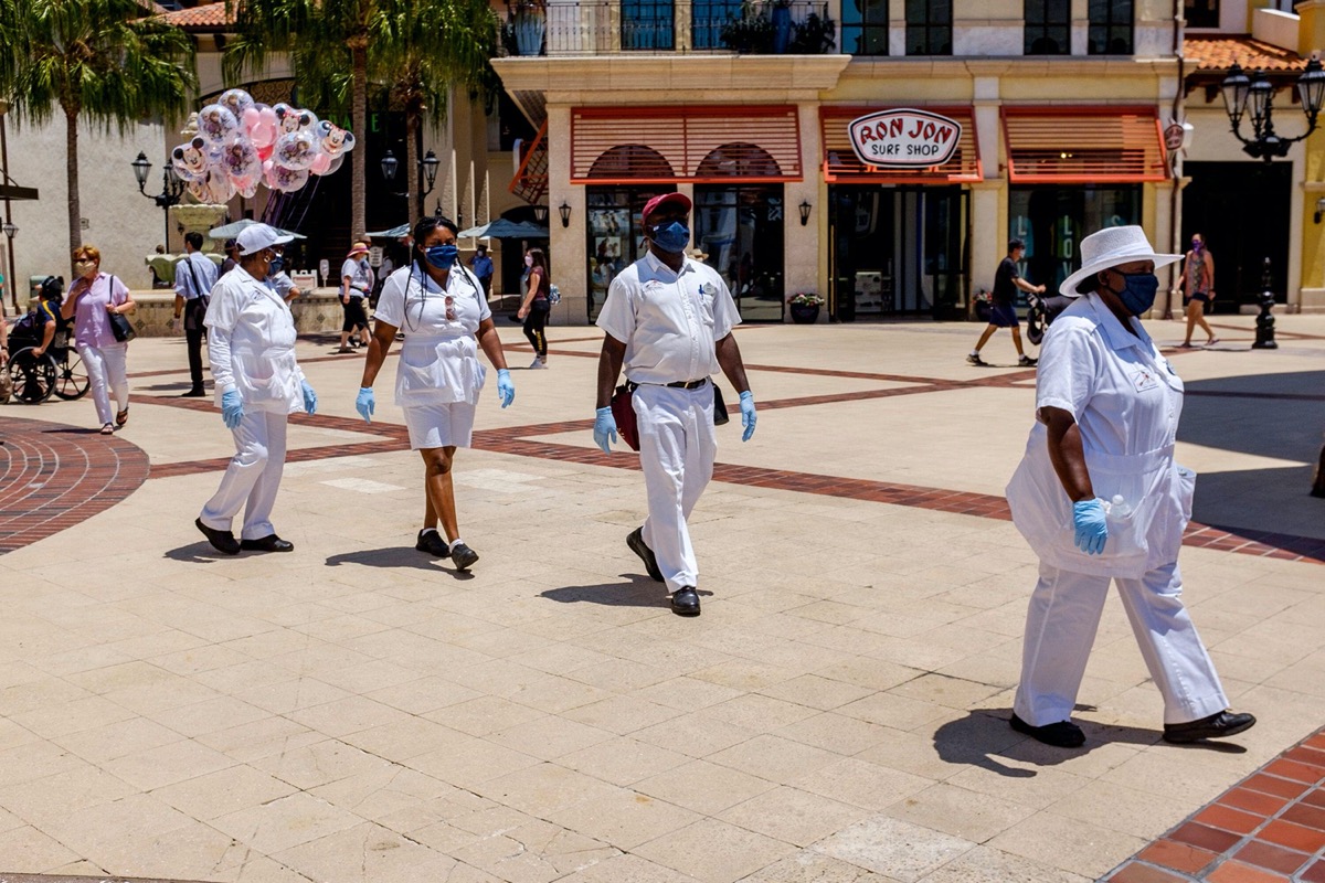 A small parade of cleaning cast members walk by during the reopening of Disney Springs