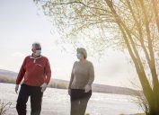 Senior couple walking trough nature with mask on face.