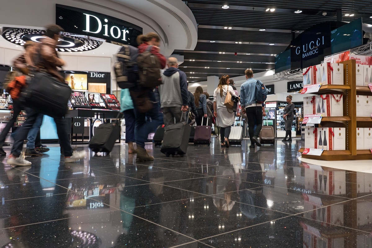 travelers walk through the duty free shops at an airport