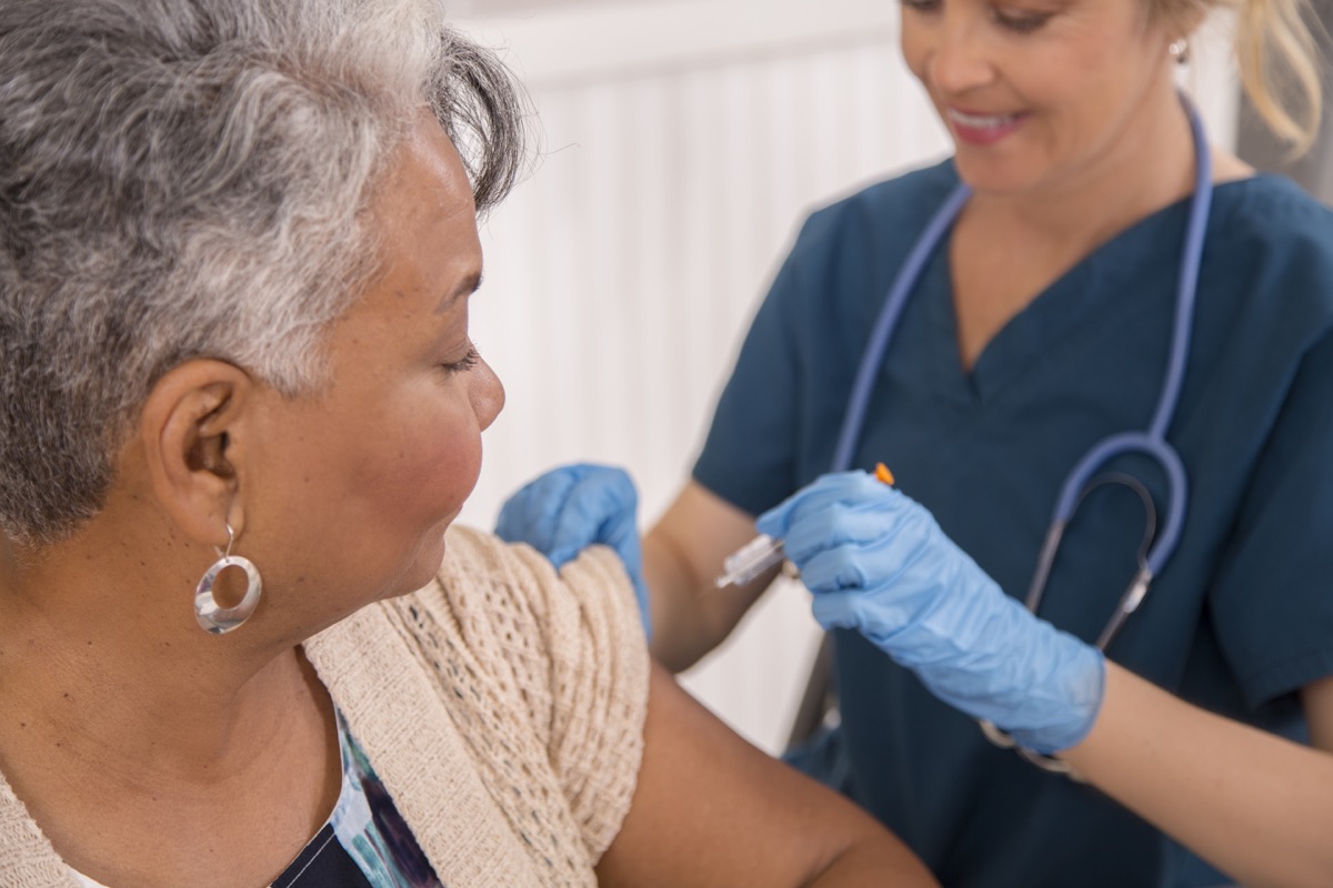 Nurse gives flu vaccine to senior adult patient at a local pharmacy, clinic, or doctor's office.